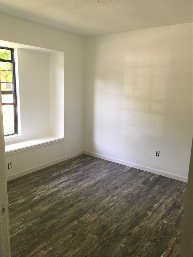 spare room with dark wood-style floors and baseboards