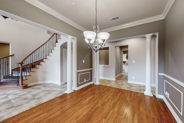 unfurnished dining area featuring decorative columns, crown molding, a chandelier, and light wood-type flooring