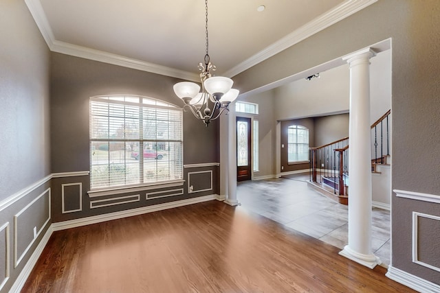 unfurnished dining area with a notable chandelier, hardwood / wood-style flooring, ornamental molding, and decorative columns