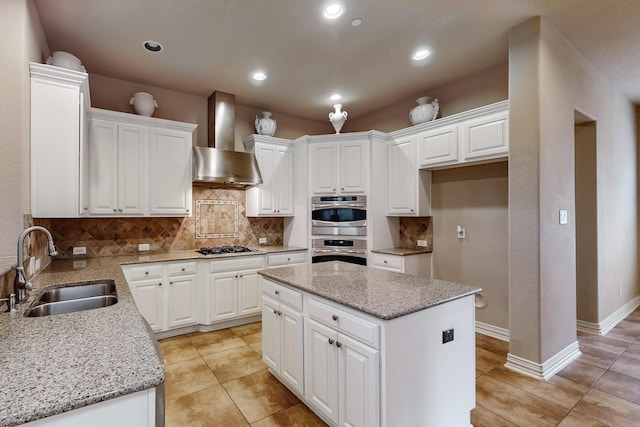 kitchen with sink, white cabinetry, a center island, light stone countertops, and wall chimney exhaust hood