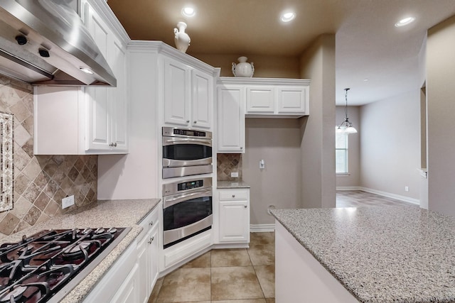 kitchen featuring white cabinetry, ventilation hood, hanging light fixtures, appliances with stainless steel finishes, and light stone countertops