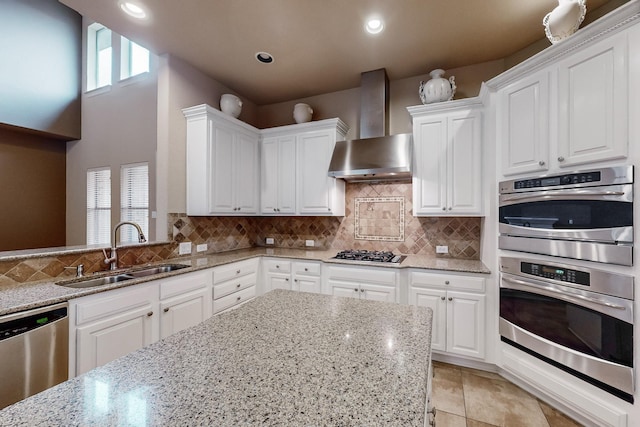 kitchen featuring white cabinetry, sink, light stone counters, stainless steel appliances, and wall chimney exhaust hood