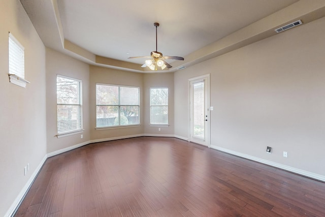 unfurnished room with ceiling fan, dark hardwood / wood-style flooring, and a raised ceiling