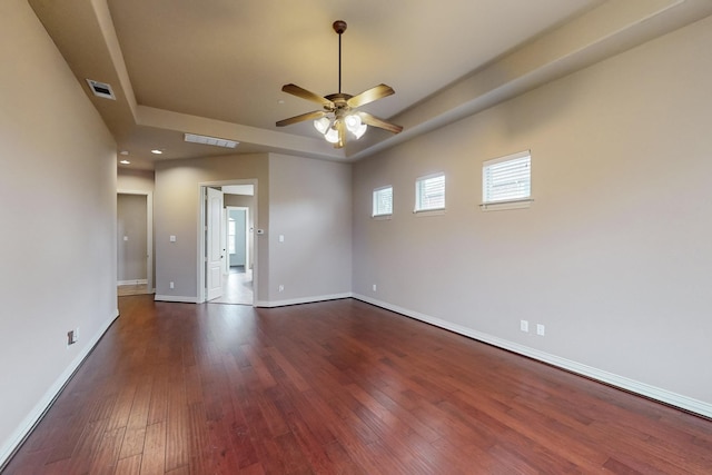 empty room featuring ceiling fan, dark hardwood / wood-style flooring, and a raised ceiling