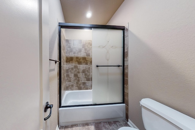 bathroom featuring toilet, bath / shower combo with glass door, and hardwood / wood-style flooring