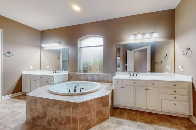 bathroom featuring a relaxing tiled tub, vanity, and tile patterned floors