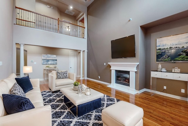 living room featuring hardwood / wood-style flooring, a high ceiling, and ornate columns