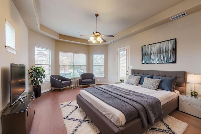 bedroom featuring hardwood / wood-style floors, a tray ceiling, and ceiling fan