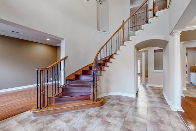 staircase featuring tile patterned floors, decorative columns, and a high ceiling