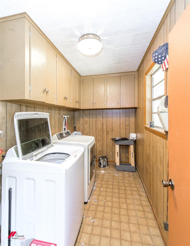 washroom featuring cabinets, independent washer and dryer, and wood walls