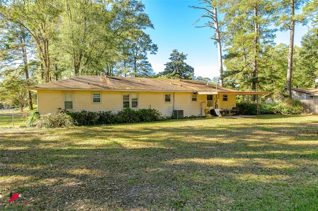 rear view of house with central AC and a lawn