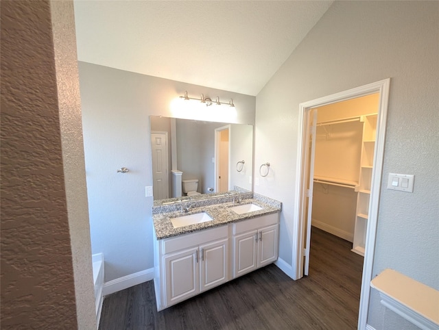 bathroom with hardwood / wood-style flooring, vanity, toilet, and lofted ceiling