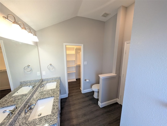 bathroom with wood-type flooring, vanity, toilet, and lofted ceiling