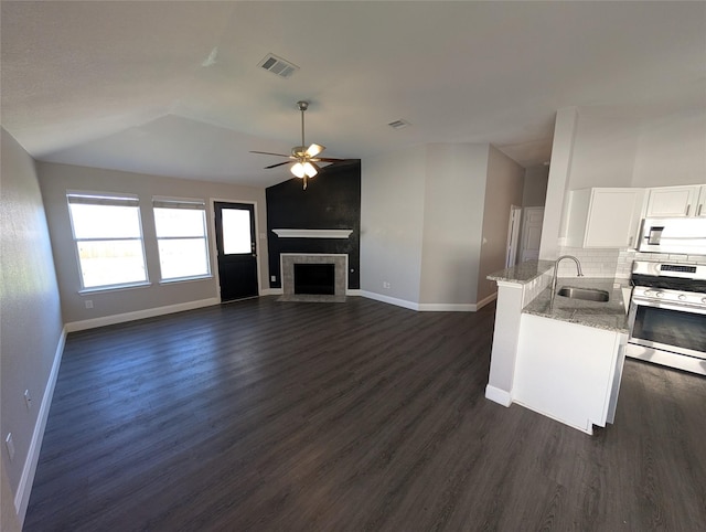 kitchen with light stone counters, stainless steel appliances, sink, white cabinets, and lofted ceiling