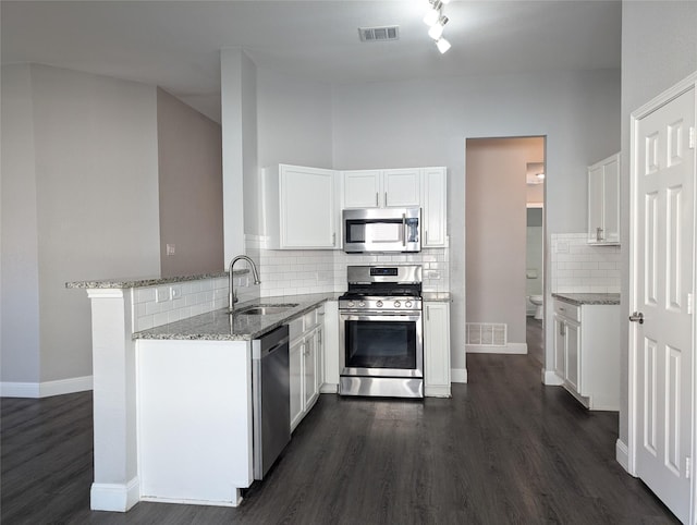 kitchen with white cabinets, sink, appliances with stainless steel finishes, light stone counters, and kitchen peninsula