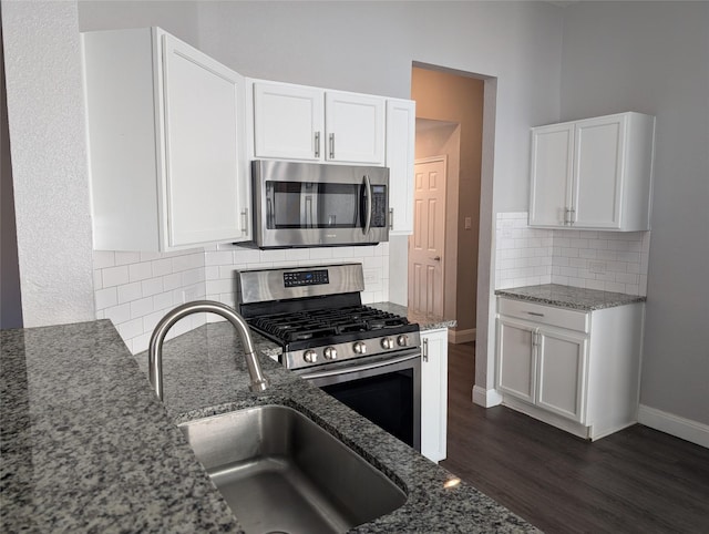 kitchen featuring white cabinetry, stainless steel appliances, and dark stone counters