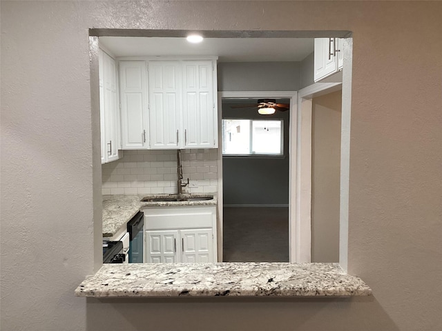 kitchen featuring white cabinets, decorative backsplash, light stone countertops, and sink