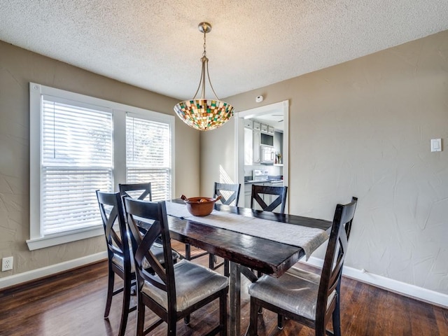 dining space featuring dark wood-type flooring and a textured ceiling