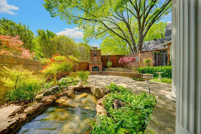 view of yard with an outdoor brick fireplace and a patio