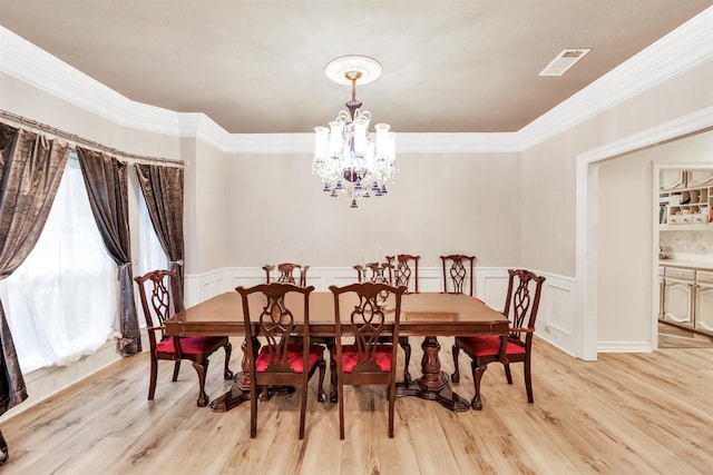 dining space featuring ornamental molding, an inviting chandelier, and light hardwood / wood-style flooring