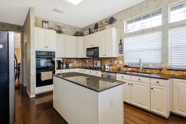 kitchen featuring sink, white cabinetry, a center island, dark stone counters, and black appliances