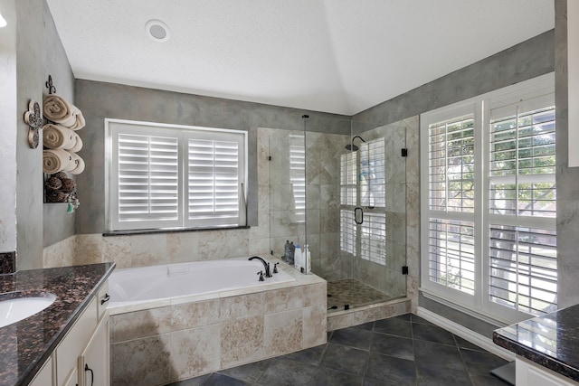 bathroom featuring tile patterned flooring, vanity, a textured ceiling, and plus walk in shower