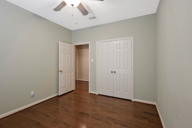 unfurnished bedroom with dark hardwood / wood-style flooring, a closet, and ceiling fan