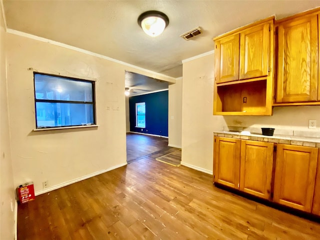 kitchen featuring crown molding, tile counters, and light wood-type flooring