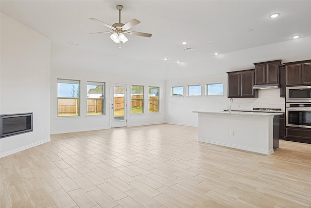 kitchen with sink, dark brown cabinets, appliances with stainless steel finishes, ceiling fan, and decorative backsplash