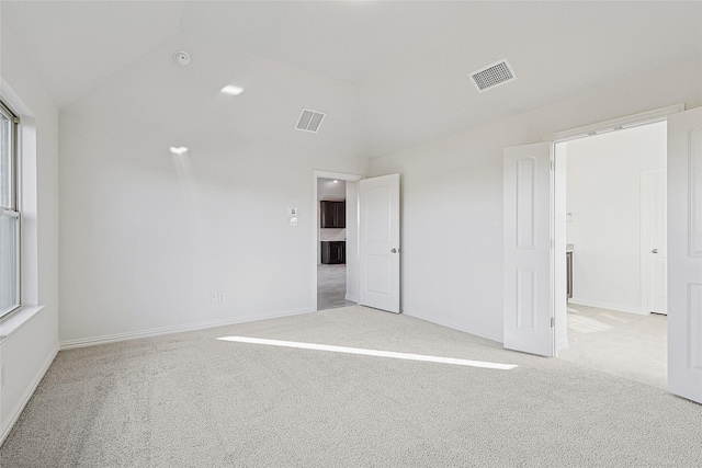 carpeted spare room with vaulted ceiling