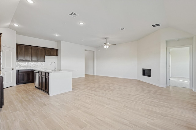 kitchen with lofted ceiling, tasteful backsplash, light hardwood / wood-style flooring, ceiling fan, and a kitchen island with sink