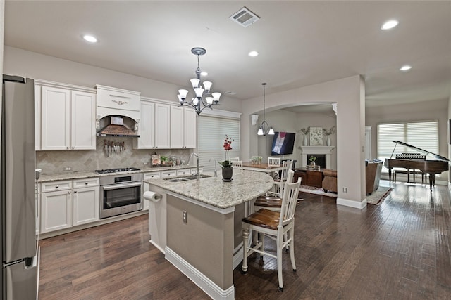 kitchen with white cabinets, decorative light fixtures, stainless steel appliances, and sink