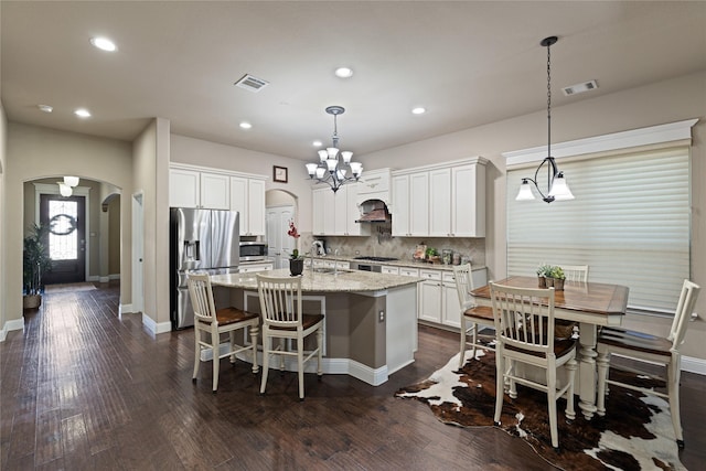 kitchen featuring white cabinets, an island with sink, hanging light fixtures, and appliances with stainless steel finishes