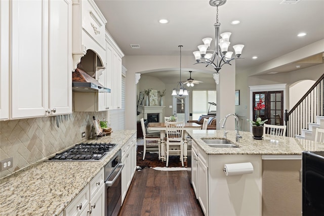 kitchen featuring appliances with stainless steel finishes, a center island with sink, white cabinetry, and hanging light fixtures