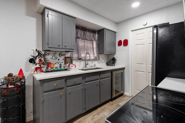 kitchen featuring gray cabinets, black refrigerator, sink, and a textured ceiling