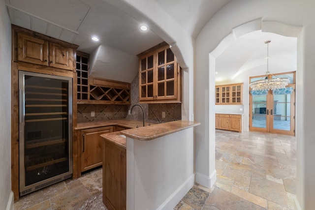 bar with sink, backsplash, beverage cooler, and decorative light fixtures