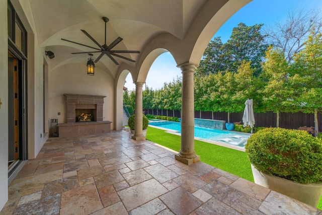 view of patio featuring a tile fireplace, a fenced in pool, and ceiling fan