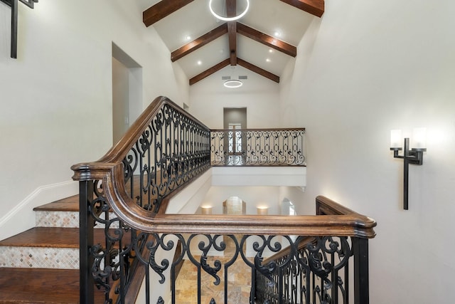 staircase with high vaulted ceiling and beam ceiling