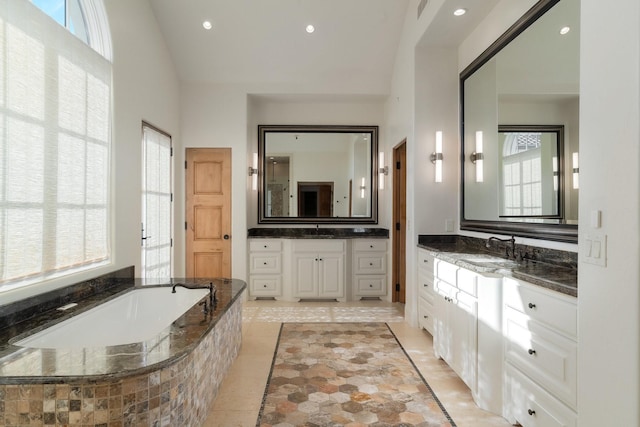 bathroom with vanity, a relaxing tiled tub, and tile patterned flooring