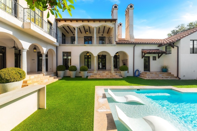 back of property featuring a balcony and a lawn