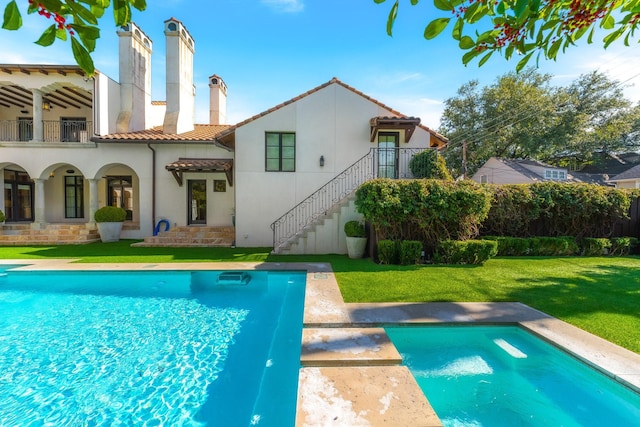 back of house with a fenced in pool, a balcony, and a yard