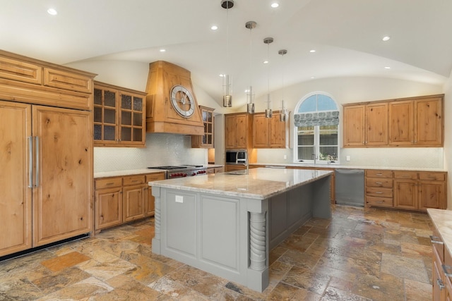 kitchen with appliances with stainless steel finishes, decorative light fixtures, light stone counters, a kitchen island, and lofted ceiling