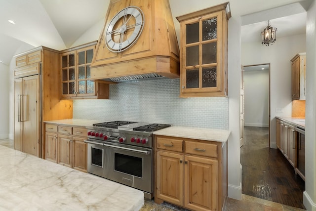 kitchen with high end appliances, decorative backsplash, premium range hood, hanging light fixtures, and vaulted ceiling