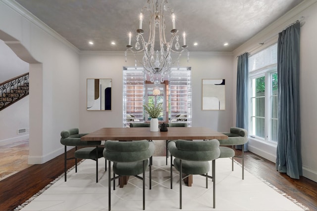 dining room featuring light hardwood / wood-style floors, a wealth of natural light, crown molding, and a notable chandelier