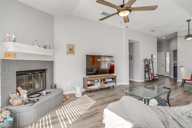 living room with wood-type flooring, a brick fireplace, ceiling fan, and lofted ceiling