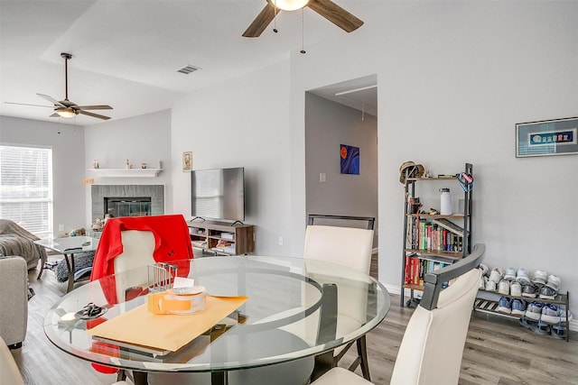 dining space featuring a fireplace, wood-type flooring, vaulted ceiling, and ceiling fan