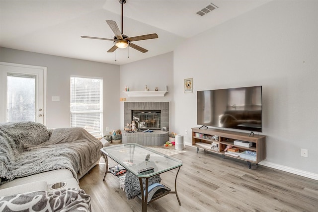 living room featuring hardwood / wood-style flooring, ceiling fan, a fireplace, and vaulted ceiling