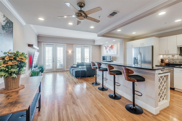 kitchen with french doors, white cabinets, crown molding, stainless steel refrigerator with ice dispenser, and decorative backsplash