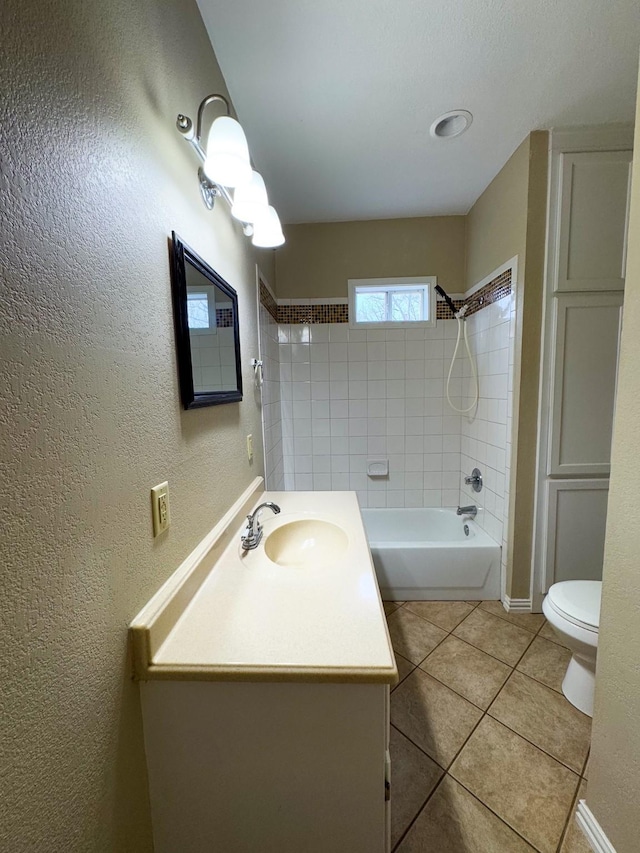 full bathroom featuring tile patterned floors, vanity, tiled shower / bath, and toilet