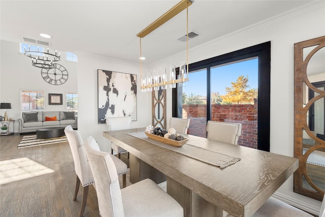 dining area featuring wood-type flooring, plenty of natural light, ornamental molding, and a chandelier